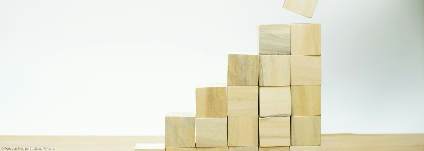 Eine Person baut aus Holzklötzen eine Pyramide