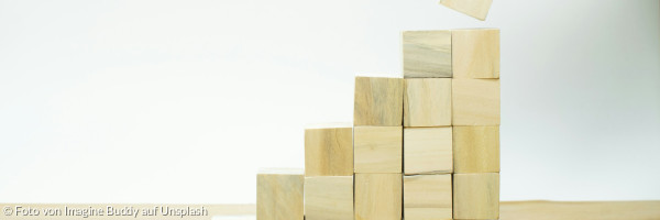 Eine Person baut aus Holzklötzen eine Pyramide